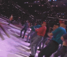 a group of people are dancing in a stadium with purple lights