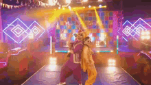 a man and a woman are dancing on a stage in a colorful room .