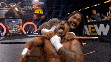a wrestler is holding another wrestler in front of an aew banner