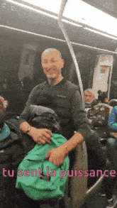 a man holding a green backpack on a train with the words " tu sent la puissance " below him