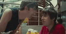 two men are talking to each other in a restaurant while sitting at a table .