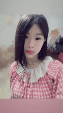 a girl wearing a pink and white checkered shirt looks at the camera