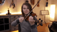 a woman is playing a violin in a room with a music stand in the background