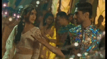 a man and a woman are dancing together at a party . the man is wearing a stained glass shirt .
