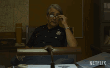 a man in a police uniform sitting at a desk with the words what do we do written below him