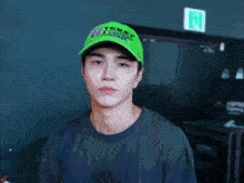 a young man wearing a green teket hat is making a peace sign
