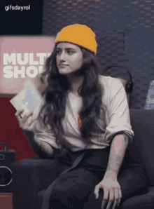 a woman wearing a yellow beanie is sitting on a couch