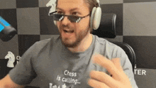 a man wearing headphones and sunglasses with the words `` chess is calling '' on his shirt .