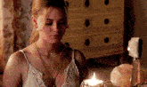 a woman is sitting in front of a lit candle in a room .