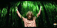 a person in a polka dot shirt is standing in front of a green curtain