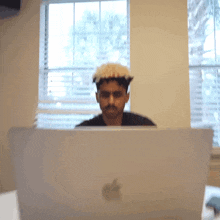 a man is sitting in front of an apple laptop computer