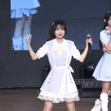 a girl in a white dress holds a microphone