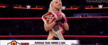 a woman is holding a wrestling belt in a wrestling ring .