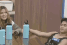 a man and a woman are sitting at a table with water bottles in front of them .