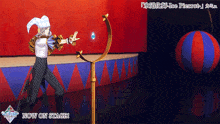 a man in a jester costume is standing on a stage with the words now on stage above him