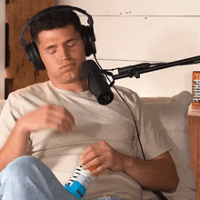a man wearing headphones is sitting in front of a microphone and a can of prime