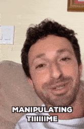 a man with a beard is sitting on a couch with a caption that says manipulating tiiiiiime