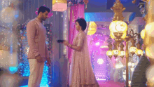 a man and a woman are standing next to each other in a room decorated with lights and flowers .