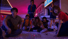 a group of people are sitting on the floor in a mall looking at something .