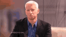 a man in a suit and blue shirt is sitting on a couch with the name anderson on the bottom
