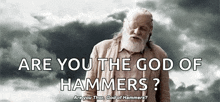 an older man with a beard is standing in front of a cloudy sky and asking are you the god of hammers ?