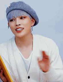 a young man wearing a grey beret and a white sweater