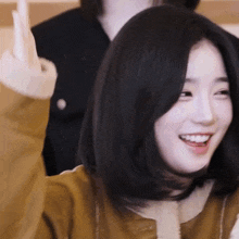 a woman in a brown jacket is smiling and giving the middle finger .