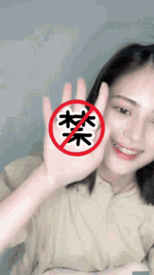 a woman holds up her hand in front of a red circle with chinese characters on it