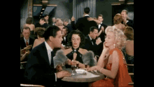 a man and two women are sitting at a table in a crowded room .