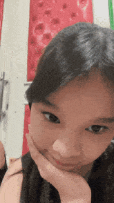 a close up of a girl 's face with her hand under her chin