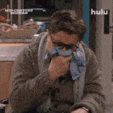 a man blowing his nose with a hulu logo in the background