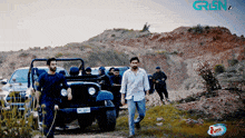 a group of men are standing in front of a jeep with the word gren on the bottom right