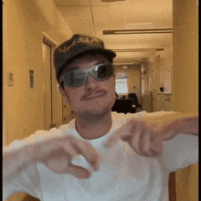 a man wearing sunglasses and a hat is pointing to the camera