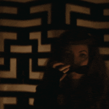 a woman stands in front of a wall with a maze pattern