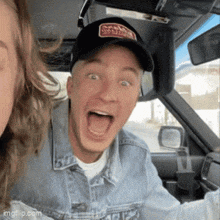 a man wearing a hat that says vans on it is driving a car