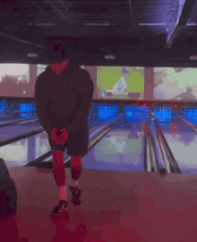 a man is kneeling down in front of a bowling alley with a tv screen behind him that says ' nfl '