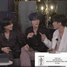 three men are sitting on a couch and one of them is pointing at something