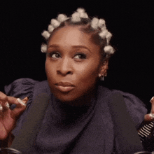 a woman with curlers in her hair is holding a bottle of lipstick