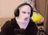 a man wearing a ski mask and headphones is playing a video game .