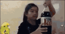 a girl is holding a large bottle of coke in her hands .
