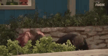 a woman is laying on the ground in front of a blue house .