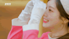 a close up of a woman wearing gloves and a pink shirt