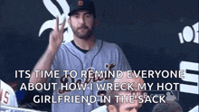 a man in a baseball uniform is giving a peace sign while sitting in the dugout .
