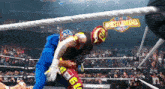 two wrestlers are fighting in a ring with a wrestlemania sign in the background