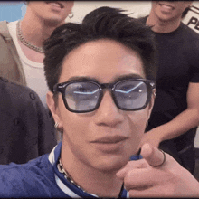 a close up of a man wearing glasses and a blue shirt with the letter g on it