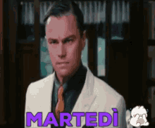 a man in a suit and tie is standing in front of a sign that says martedi