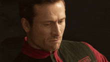 a man wearing a red and black jacket with the word woods on it