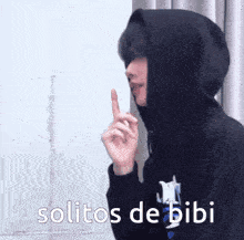 a person wearing a black hoodie has their finger on their lips and the words solitos de bibi above them