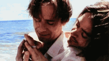 a man is holding another man 's hand on the beach .