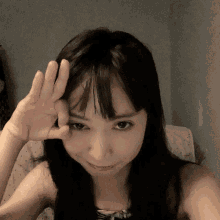 a woman with long black hair is making a face with her hand